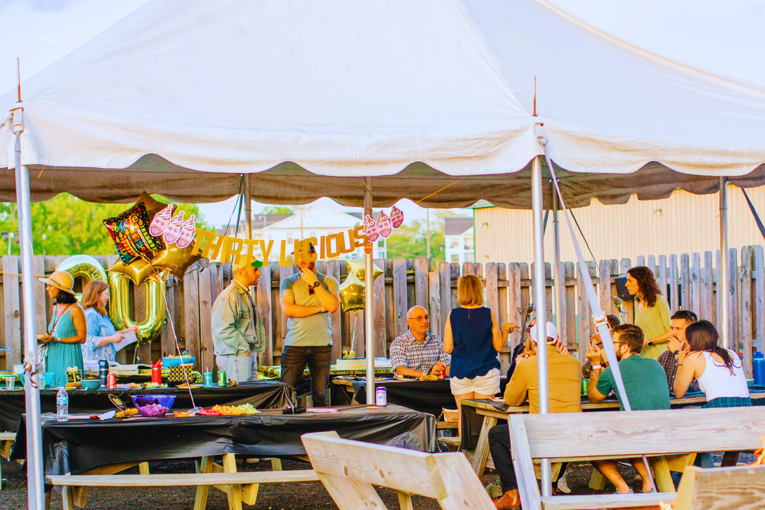 People gathered under a large white tent at a party.